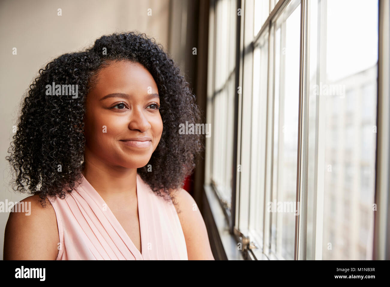 Junge schwarze Frau aus dem Fenster schauen, lächeln, Nahaufnahme Stockfoto