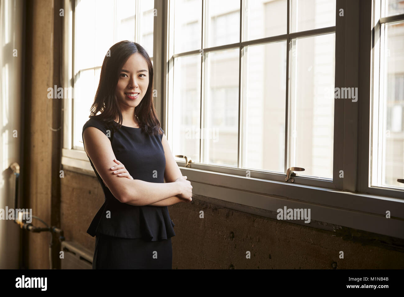 Lächelnde junge chinesische Geschäftsfrau zu Kamera Stockfoto