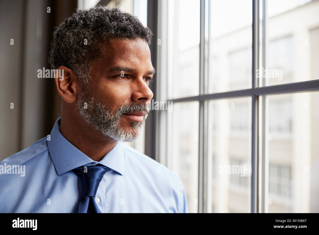 Im mittleren Alter schwarzer Geschäftsmann Blick aus Fenster Stockfoto