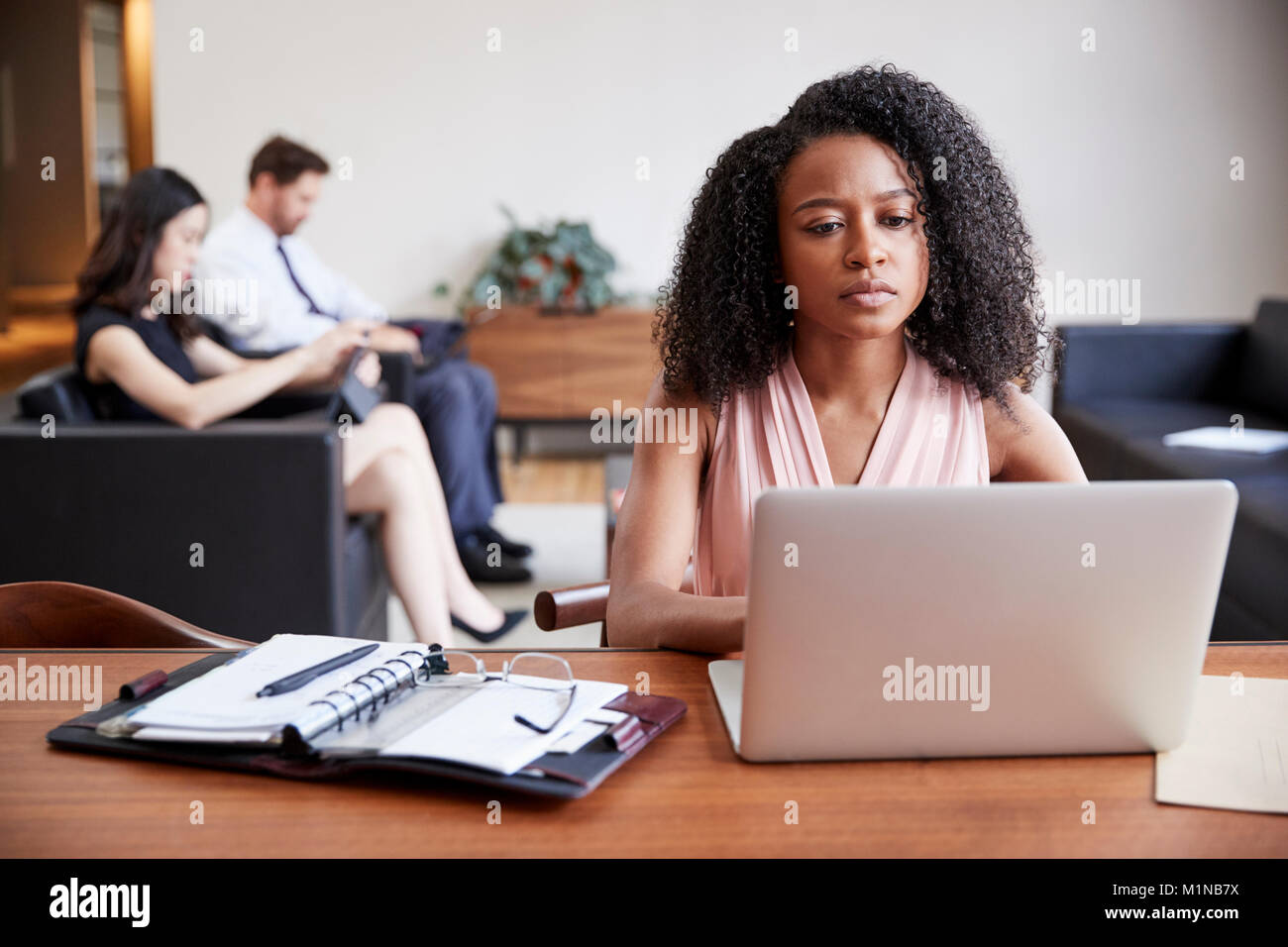 Junge schwarze Geschäftsfrau mit Laptop an einem Schreibtisch Stockfoto