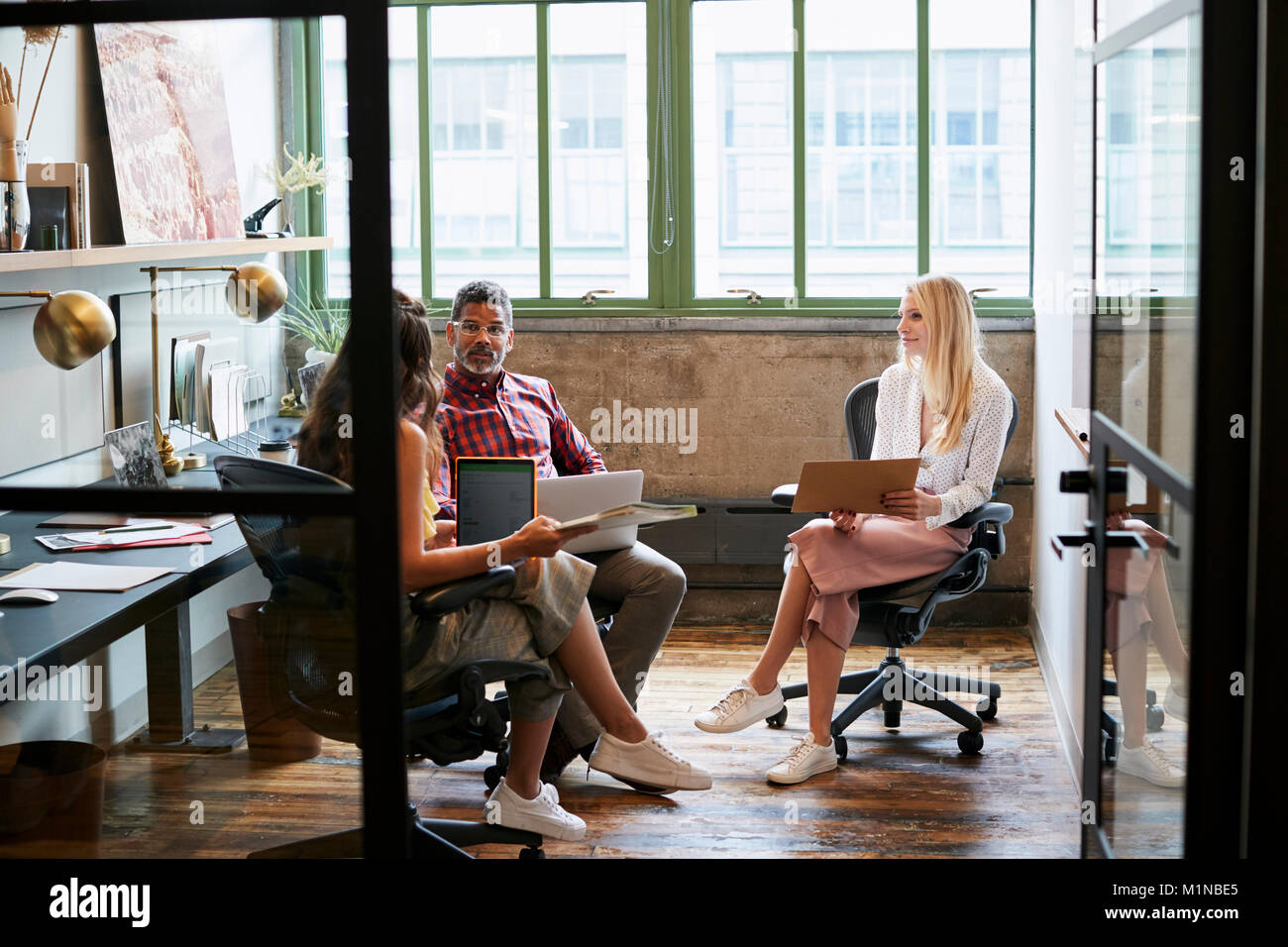 Drei Mitarbeiter in einem Team Meeting, die durch offene Tür gesehen Stockfoto