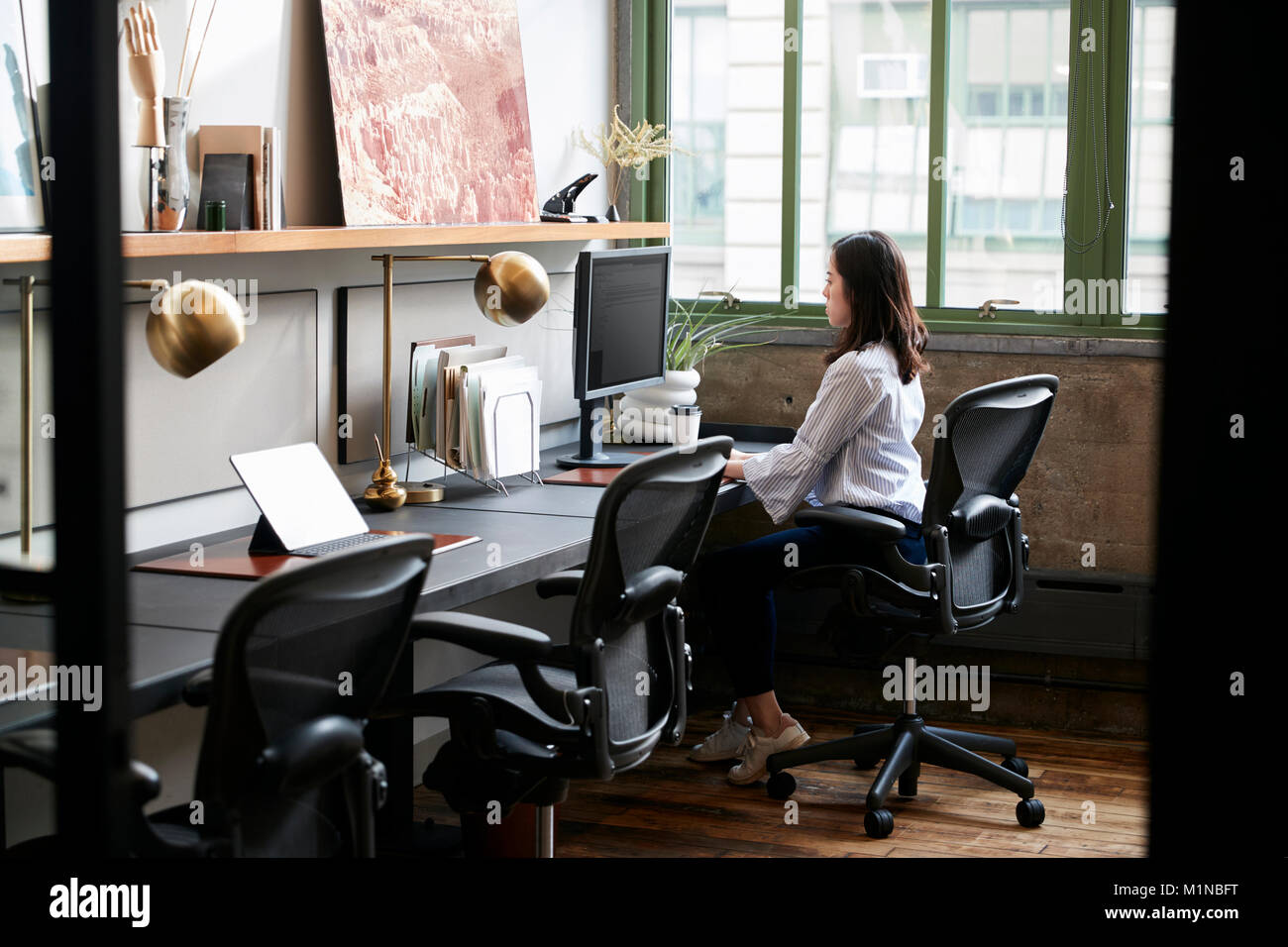 Junge Frau alleine in einem kompakten Büro Stockfoto