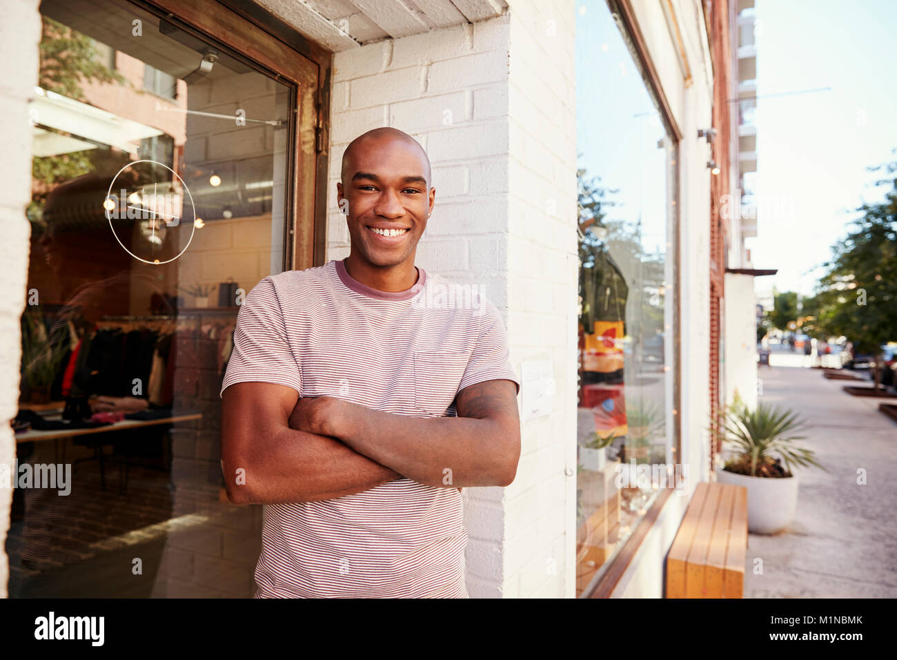 Junge schwarze Mann lächelnd Kamera außerhalb seiner Kleidung Shop Stockfoto