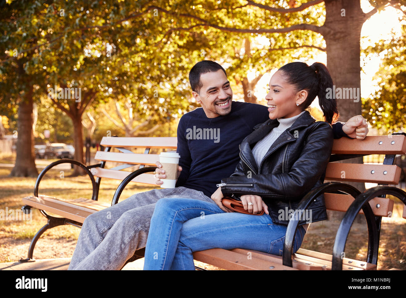 Junge Hispanic Paar sitzt auf der Bank in Brooklyn Park Stockfoto