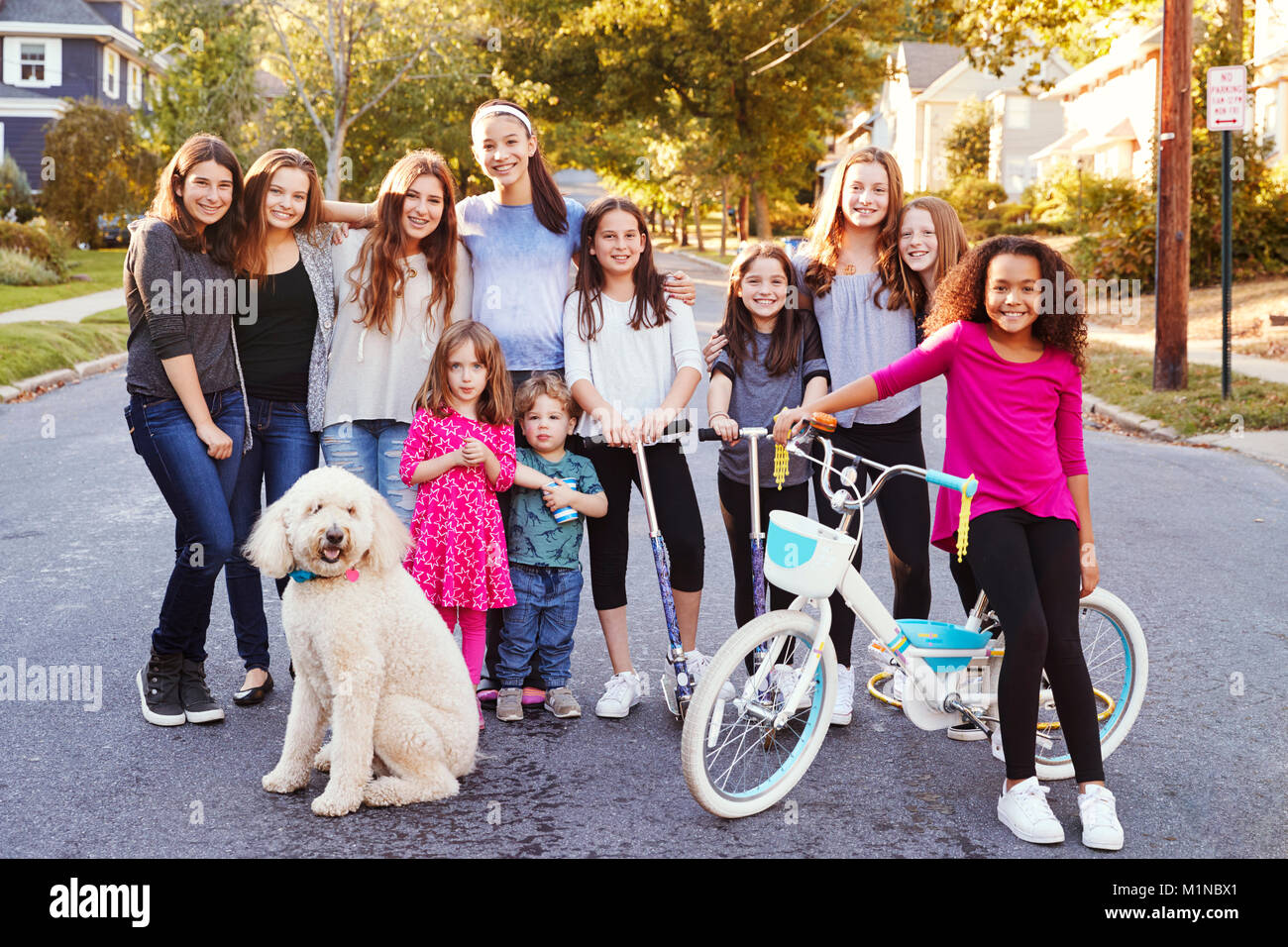 Gruppe von Kindern mit Hund lächeln in die Kamera in einer Wohnstraße. Stockfoto