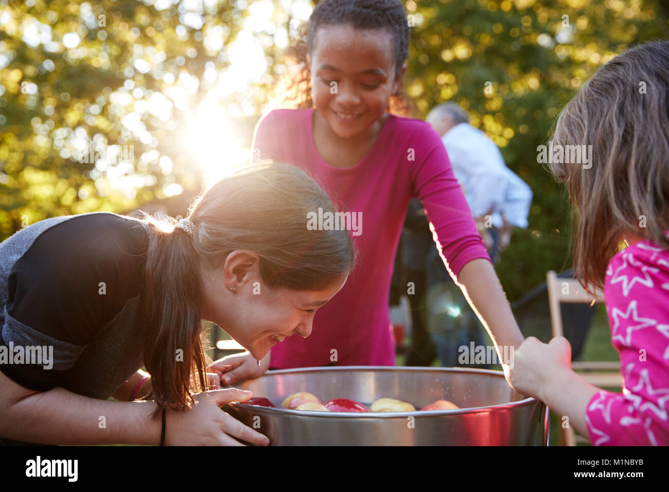 Junge Mädchen lachen während Apple bobbing in einem Hinterhof Partei Stockfoto