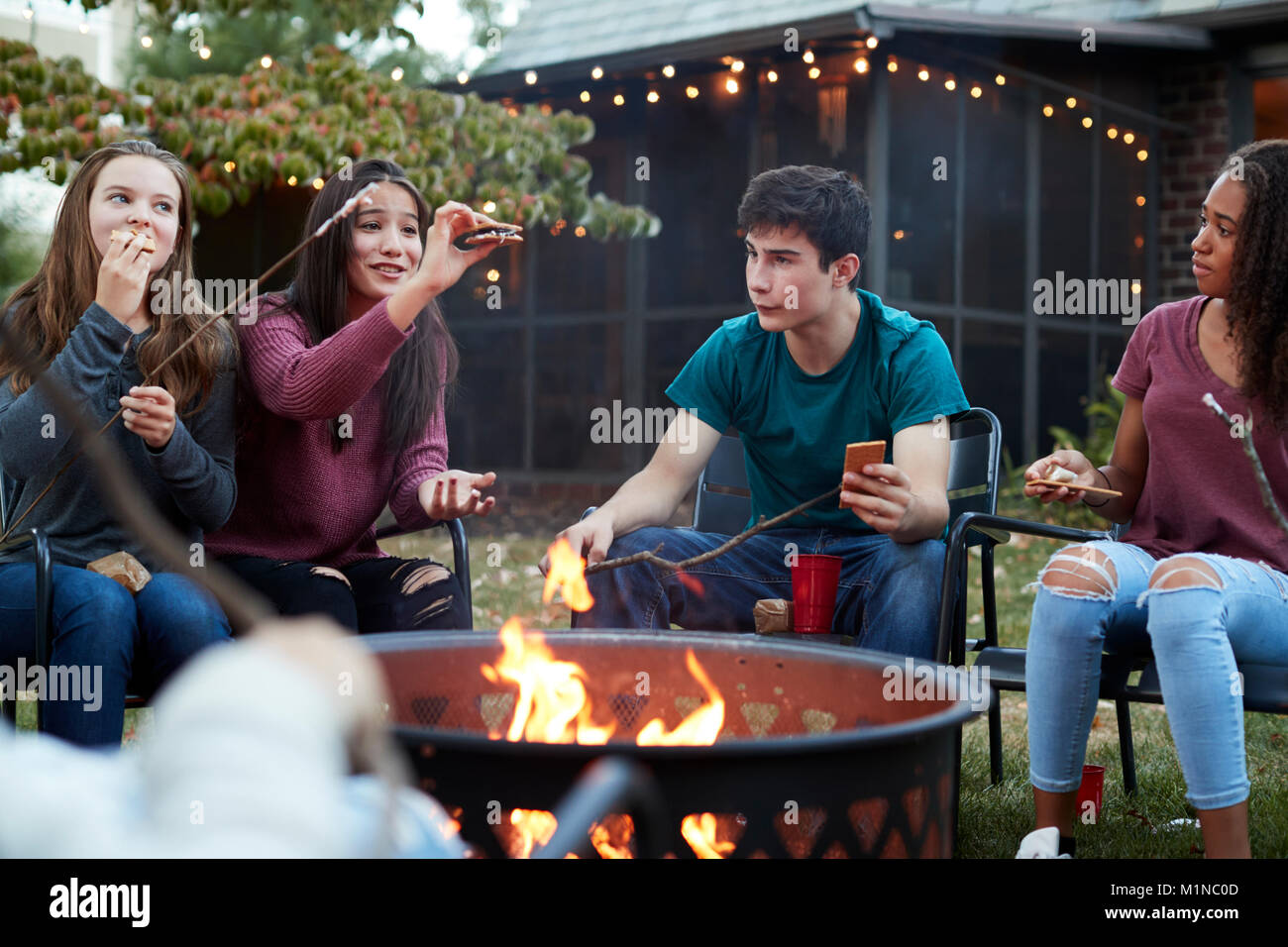 Teenage Freunde essen s'mores um eine Feuerstelle Stockfoto