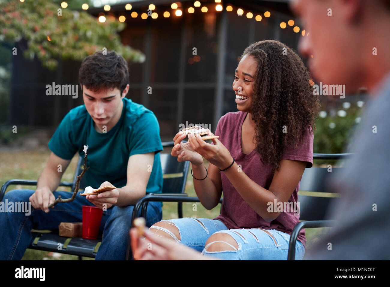 Schwarze Mädchen im Teenageralter, s'More mit Freunden an einer Feuerstelle Stockfoto