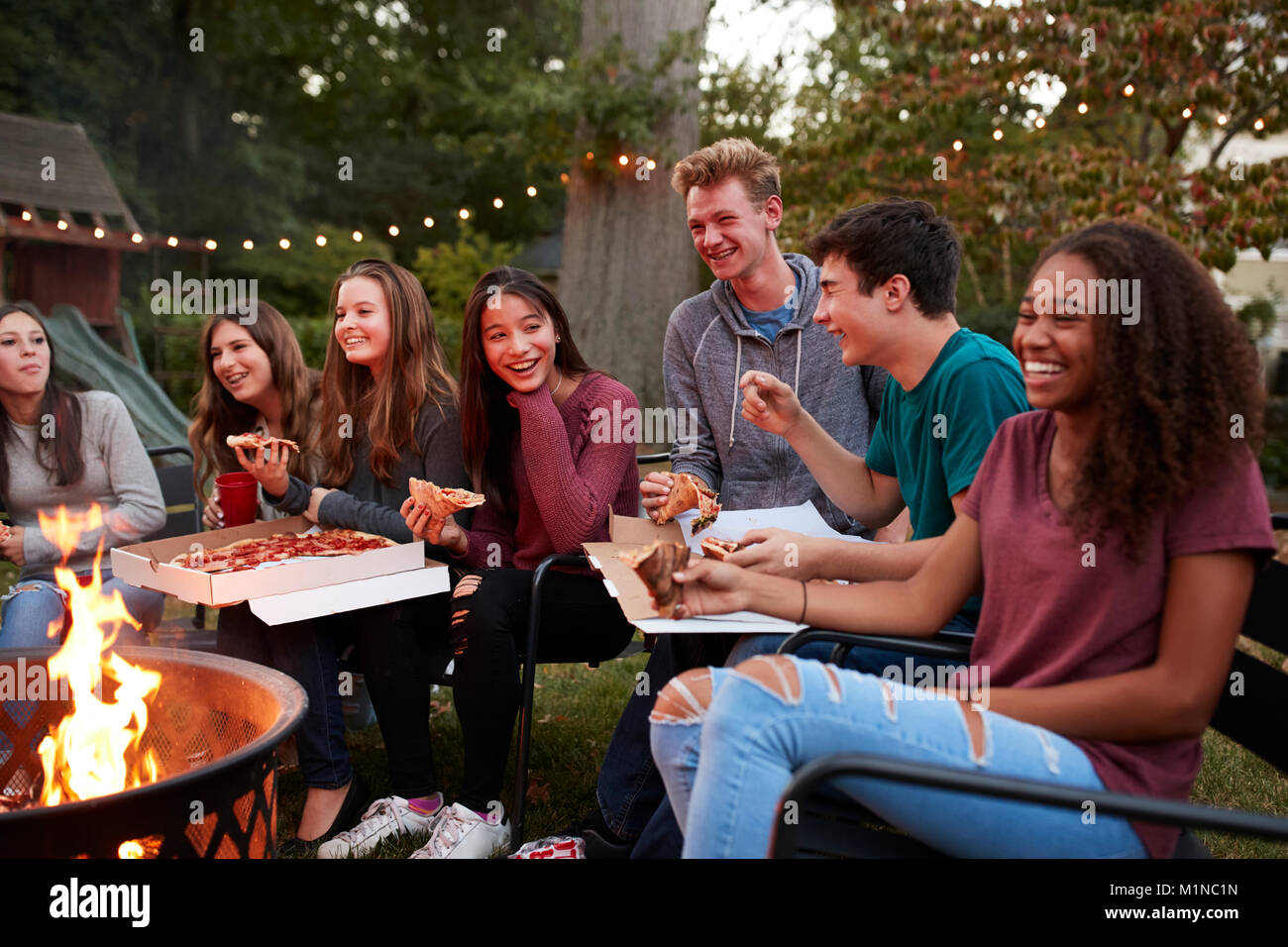 Jugendliche an einer Feuerstelle essen Pizza zum Mitnehmen, in der Nähe Stockfoto