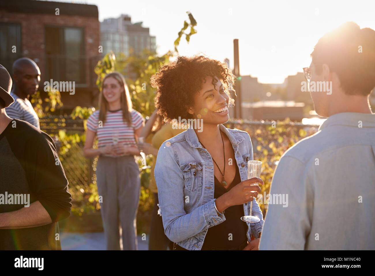 Freunde sprechen auf eine Dachterrasse Partei durch Sonnenlicht mit Hintergrundbeleuchtung Stockfoto Freunde sprechen auf eine Dachterrasse Partei durch Sonnenlicht mit Hintergrundbeleuchtung Stockfoto