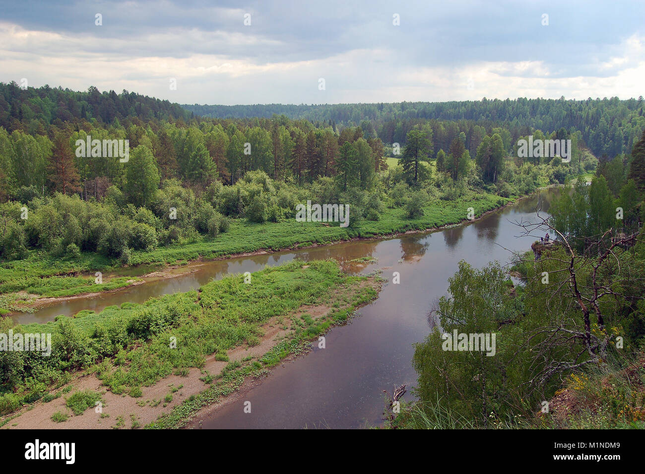 Blick vom Berg ins Tal des Flusses unter den gering bewaldeten Hügeln im regnerischen Wetter Stockfoto