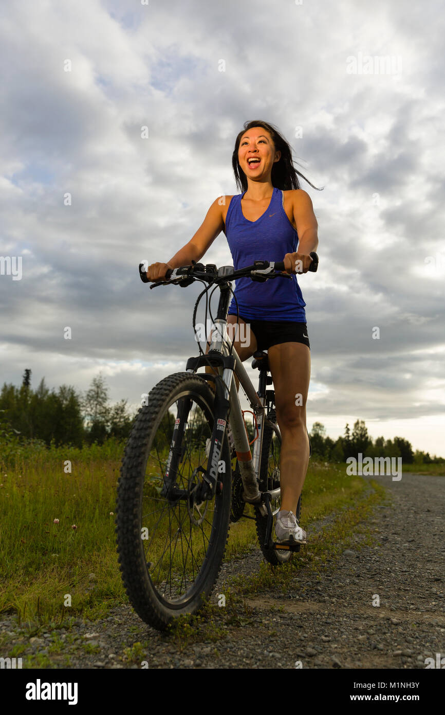 Frau Reiten Fahrrad auf gemeinsamer Basis Elmendorf Richardson an Six Mile Lake in der Nähe von Anchorage in Southcentral Alaska. Stockfoto
