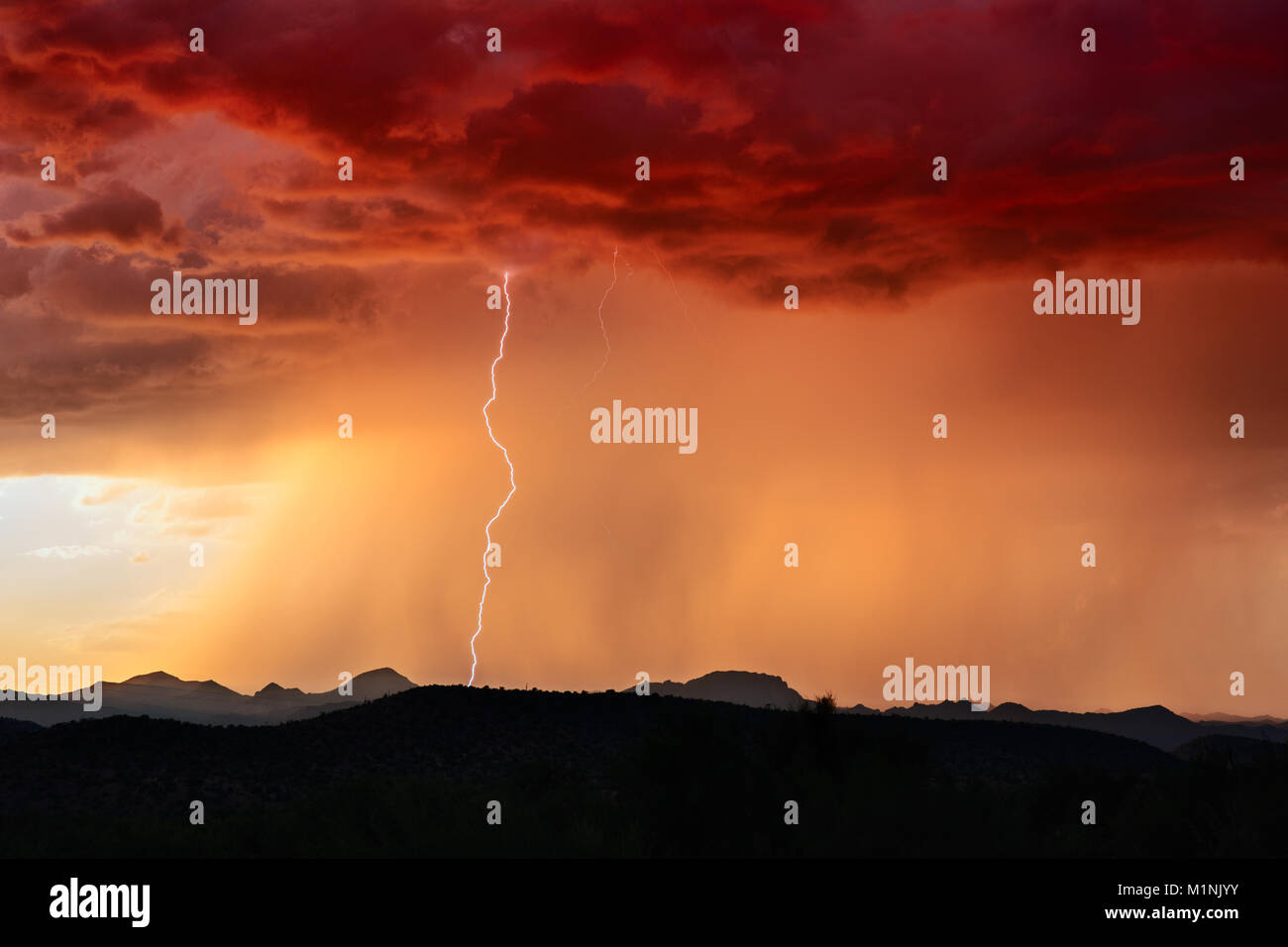 Bei einem Sommergewitter in der Nähe von Wickenburg, Arizona, schlagen Blitzeinschläge bei Sonnenuntergang über den Bergen ein Stockfoto