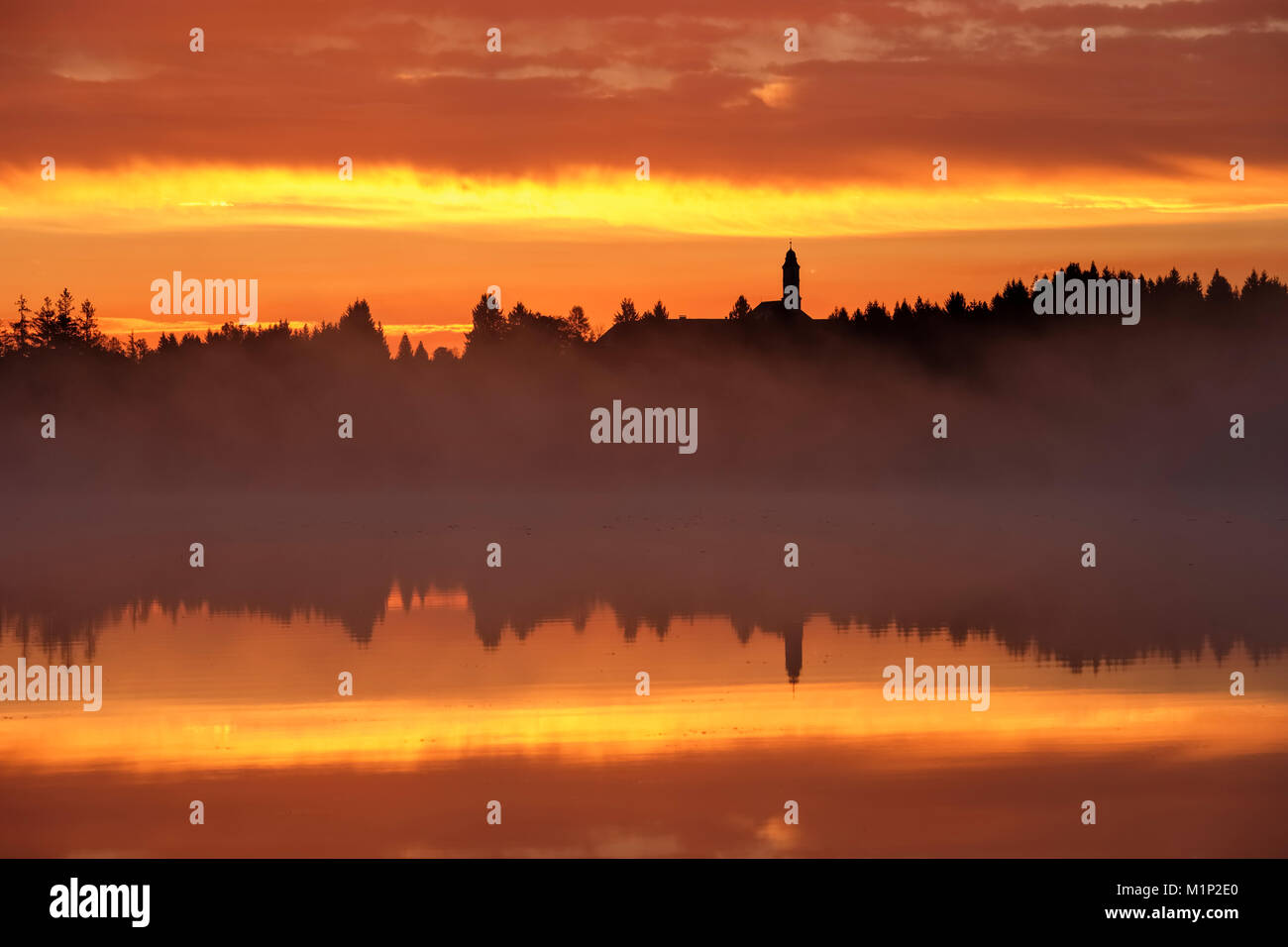 Sonnenaufgang, Dämmerung, am frühen Morgen Nebel über Kirchsee mit Kloster Reutberg, Sachsenkam, Tölzer Land, Oberbayern, Bayern Stockfoto