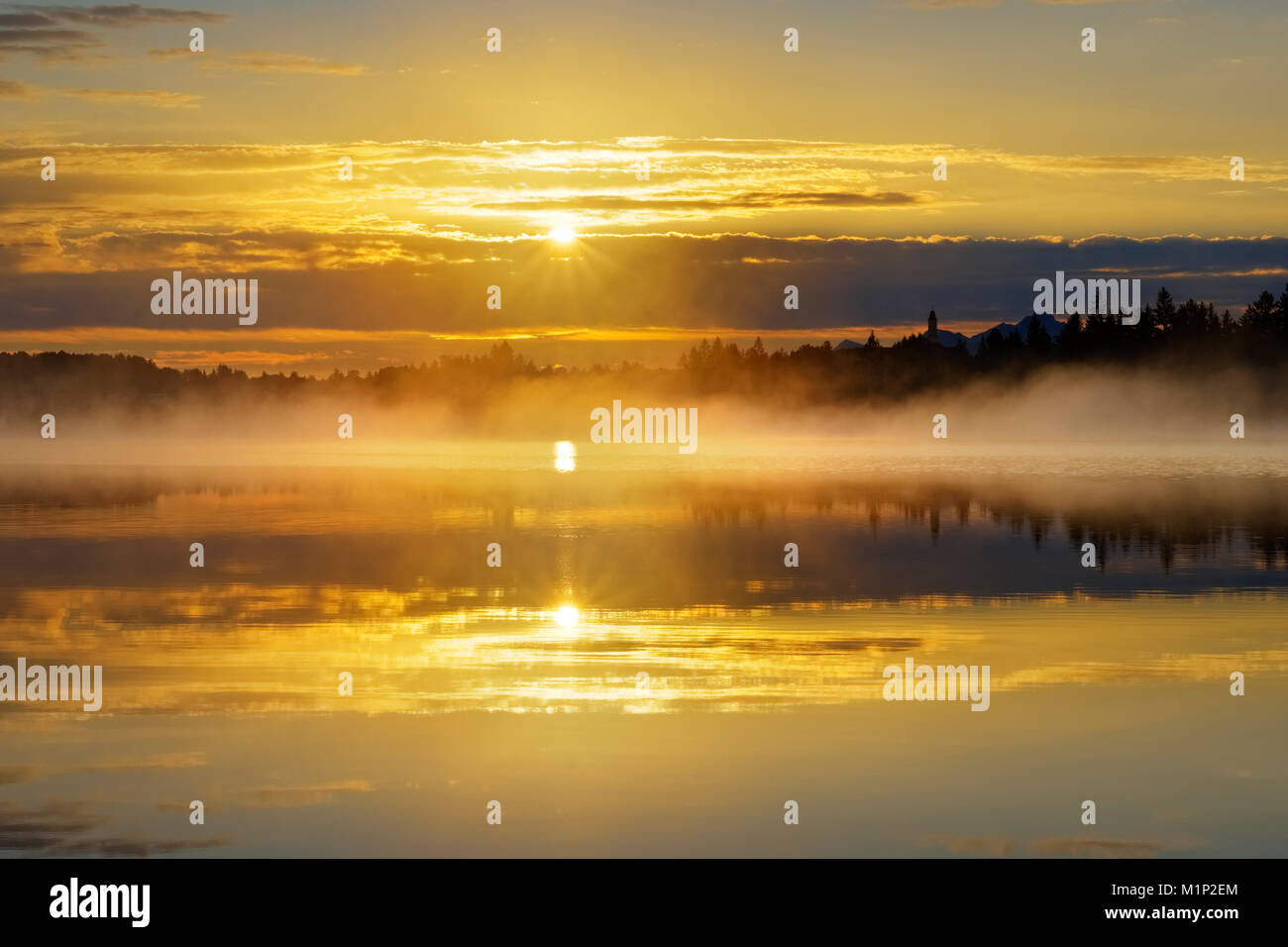 Sonnenaufgang mit frühen Morgennebel über Kirchsee mit Kloster Reutberg, Sachsenkam, Oberbayern, Bayern, Deutschland Stockfoto