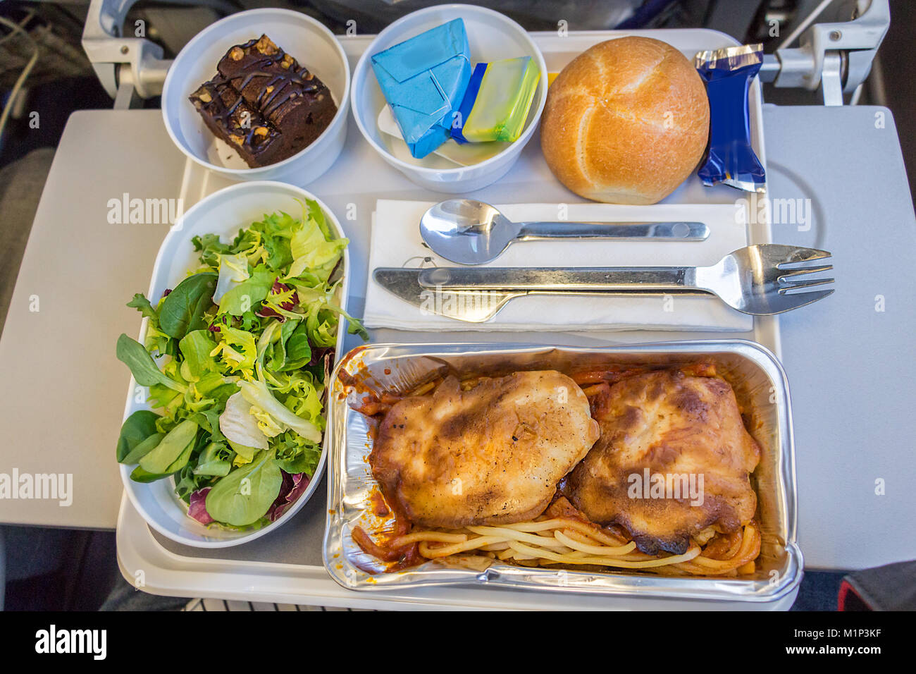 Ein Abendessen an Bord Mahlzeit mit Pasta, Huhn, Käse, Butter, Schokolade Dessert und Brot auf einem Tablett an Bord eines langen Flug von Europa nach Amerika im Eco Stockfoto