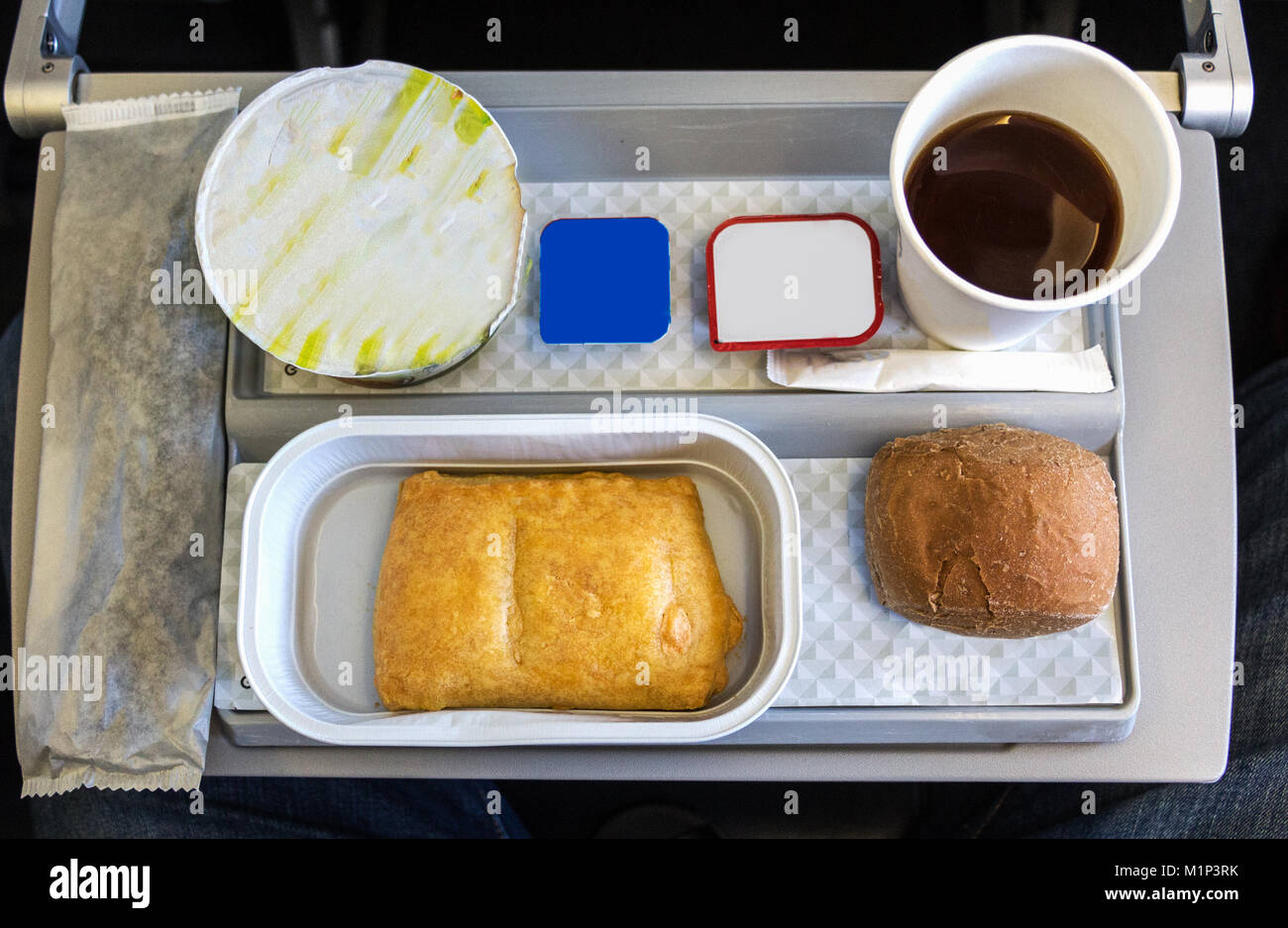 Ein Frühstück mit Kaffee, Butter, Brot und Joghurt auf einem Tablett, an Bord einen kurzen Flug in der Economy Class in Europa. Stockfoto