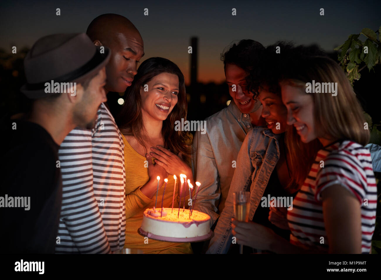 Junge Erwachsene feiern mit einem Geburtstagskuchen auf dem Dach Stockfoto