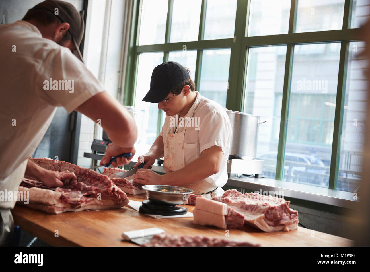 Zwei Metzger schneiden von Fleisch in eine Metzgerei zu verkaufen Stockfoto