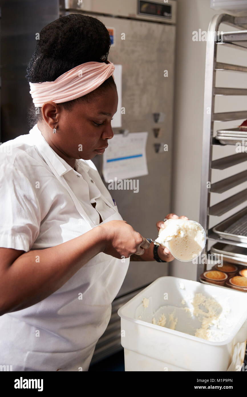 Junge schwarze Frau an einer Bäckerei Vorbereitung Kuchen Glasur Stockfoto