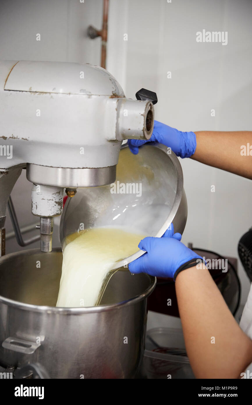 Frau gießen Backmischung in eine große Schüssel an einer Bäckerei Stockfoto
