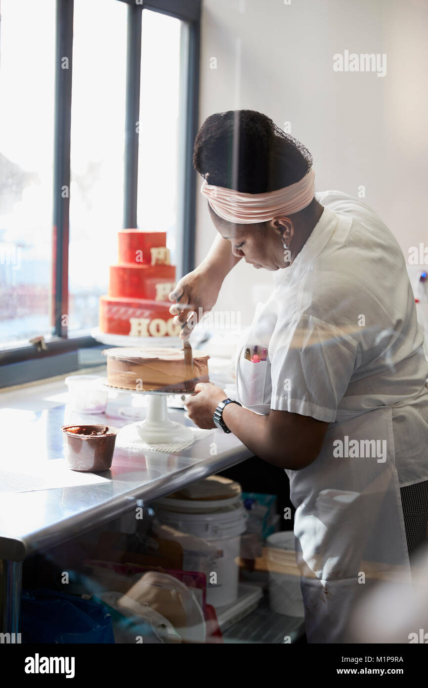 Junge schwarze Frau Zuckerguss Kuchen beim Bäcker Stockfoto