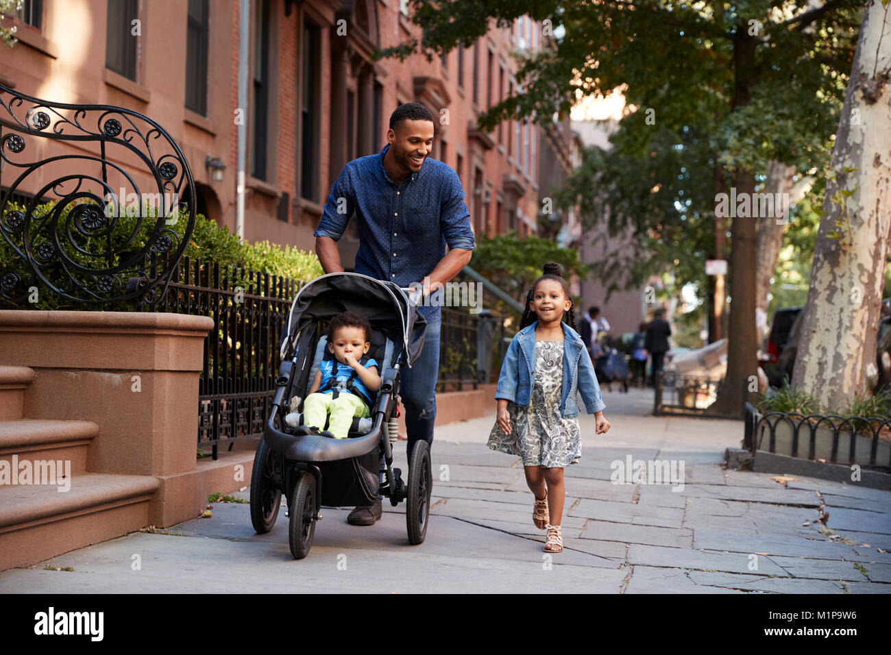 Vater und zwei Töchter bei einem Spaziergang die Straße runter Stockfoto