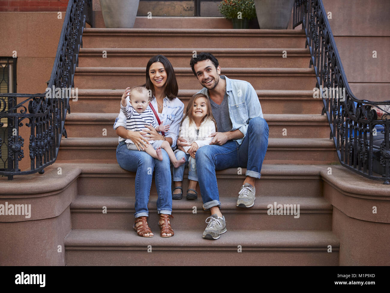 Junge Familie mit Kindern sitzt auf der vorderen Stoops Stockfoto