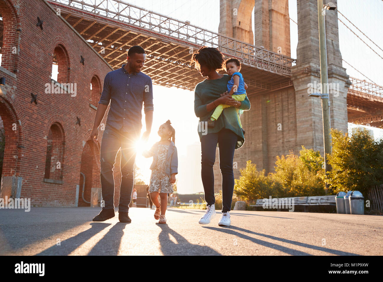 Junge Familie mit zwei Töchtern zu Fuß auf einer Straße Stockfoto