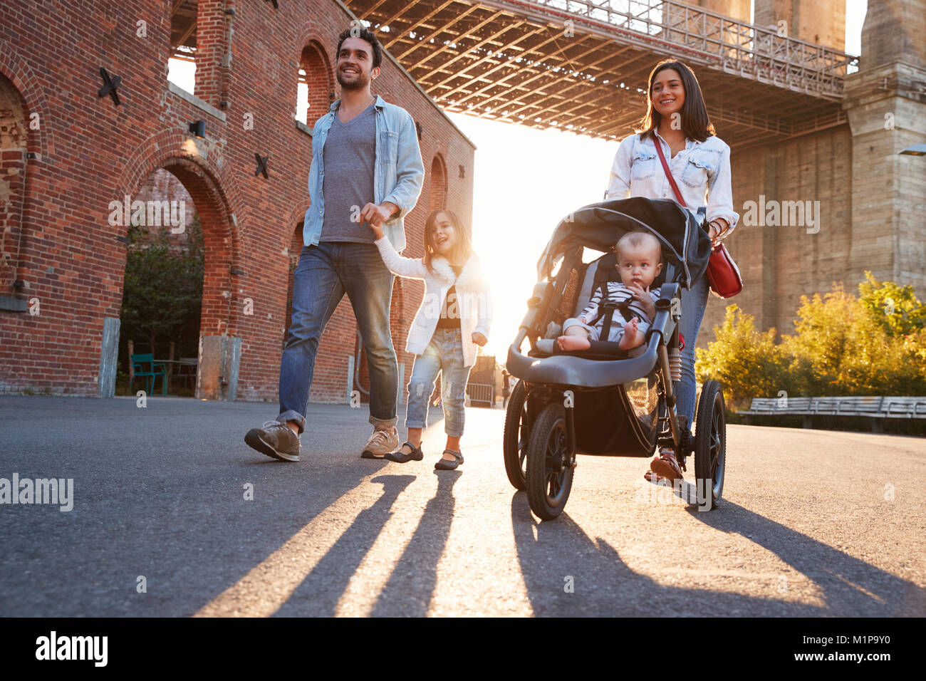 Junge Familie mit zwei Töchtern zu Fuß auf einer Straße Stockfoto