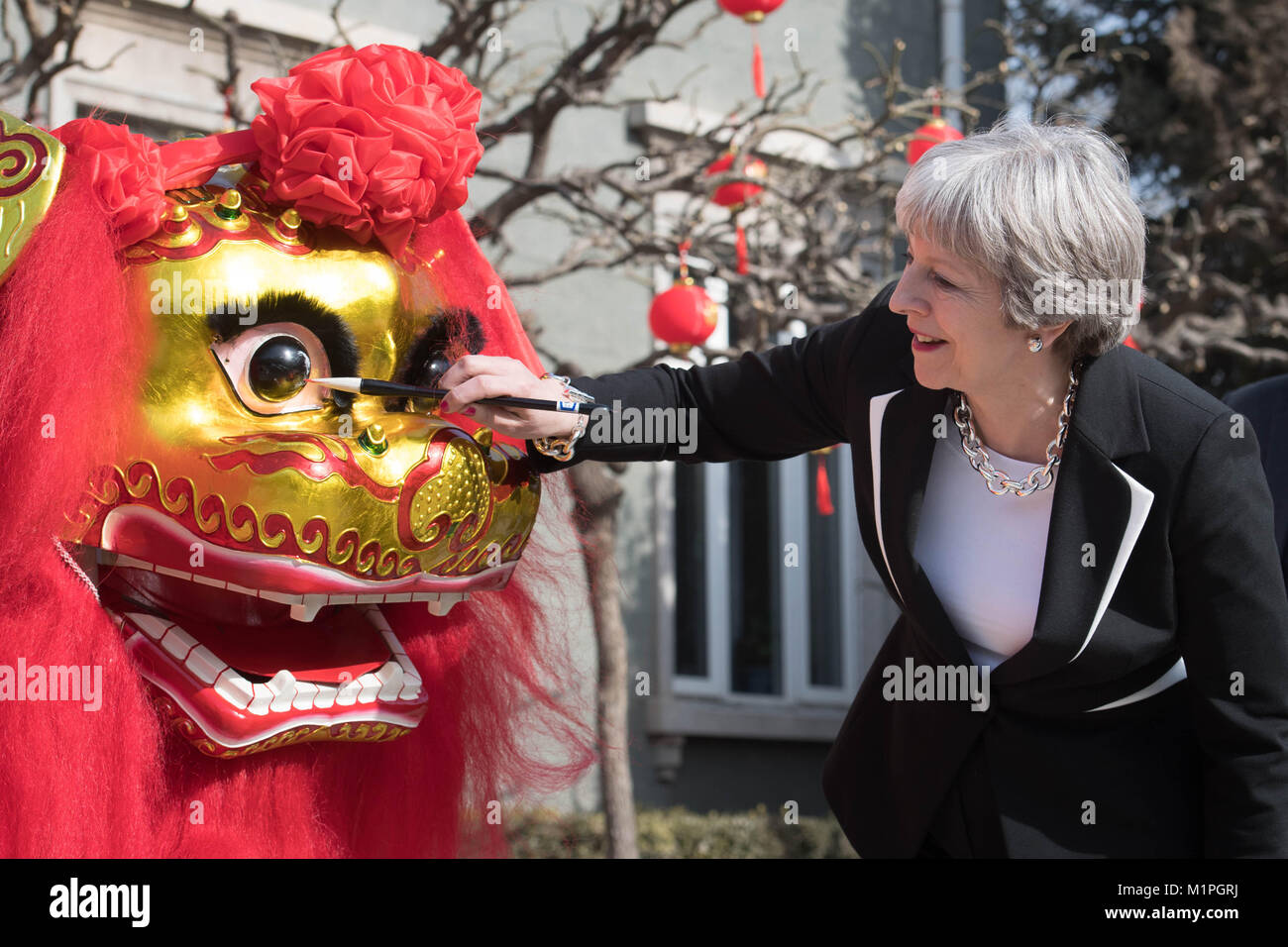 Premierminister Theresa 'Dots' das Auge eines chinesischen Drachen, einem traditionellen Ritual des Erwachens ein Drache, auf dem Gelände der Britischen Botschaft in Peking heute am zweiten Tag einer dreitägigen Delegationsreise nach China. Stockfoto