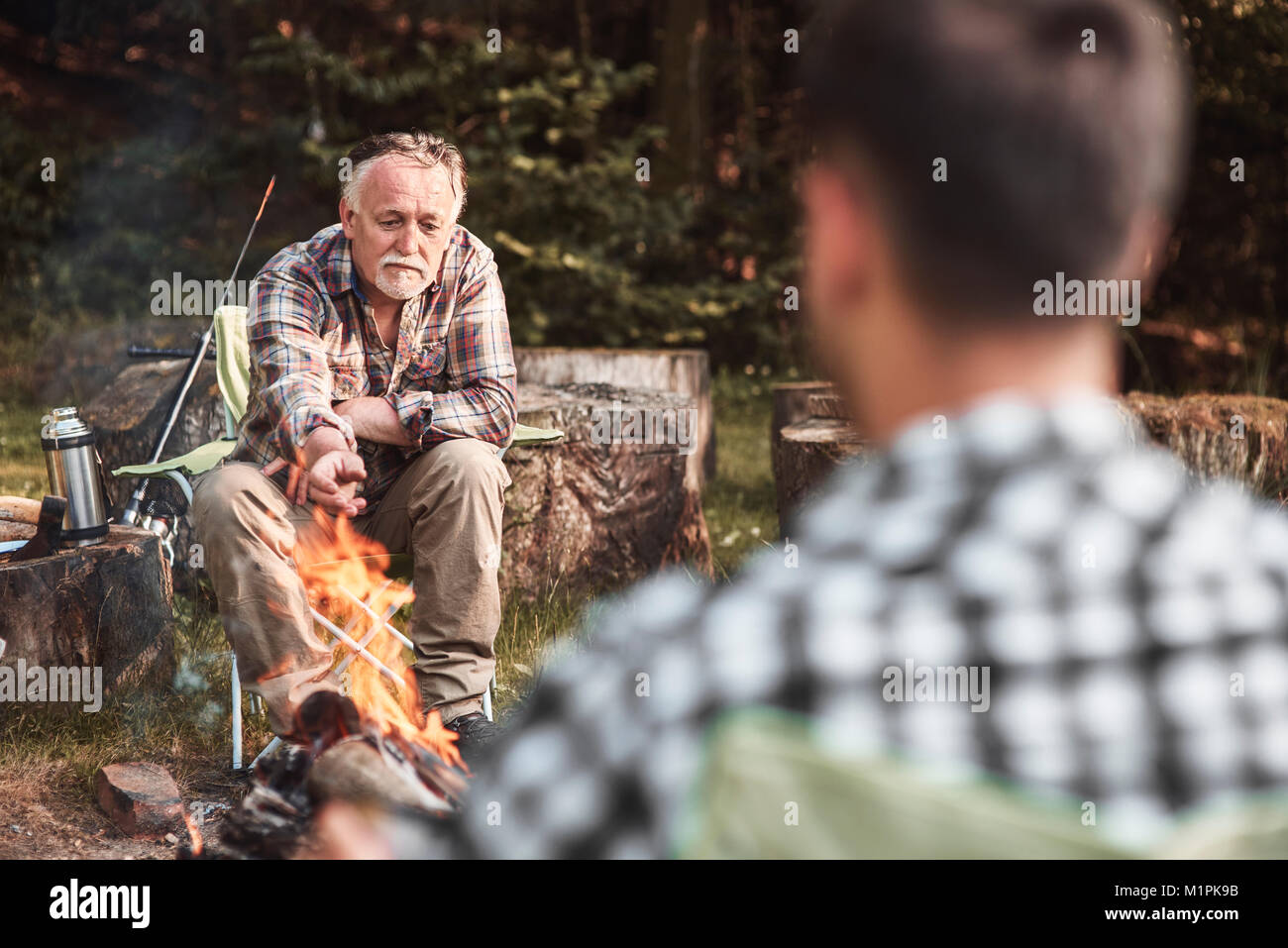 Mann sitzt am Lagerfeuer beim camping im Wald Stockfoto