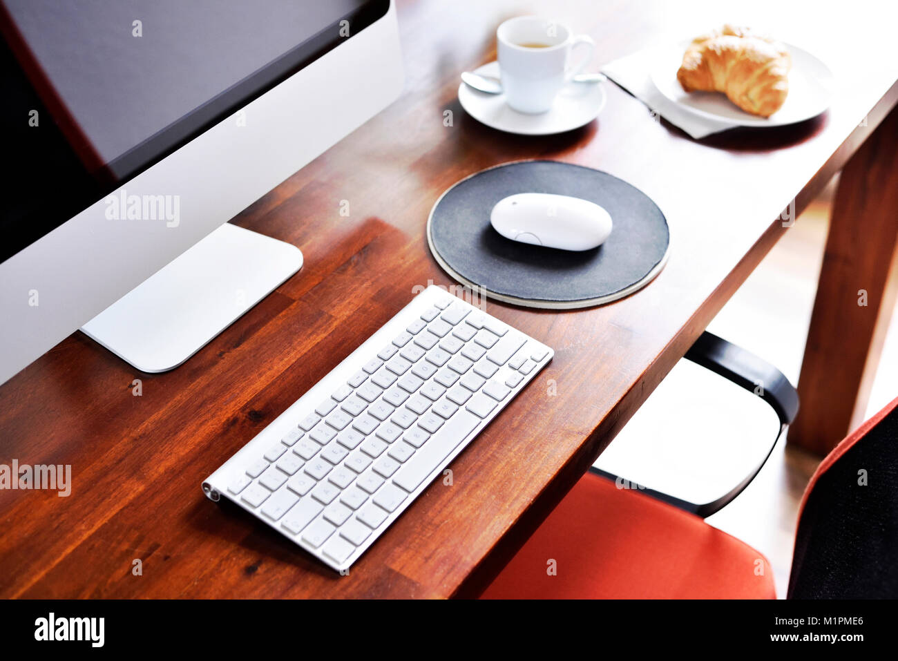 Arbeitsplatz Szene mit Frühstück. Frühstück Hintergrund auf einem Arbeitsplatz, Croissant und Kaffee Tasse. Computer, Snacks und heiße Getränke, Büro Szene, brechen. Stockfoto