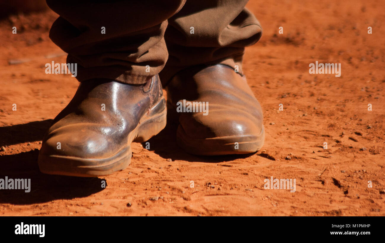 Ein paar schmutzige, staubige reiten Stiefel an den Füßen einer Territorian vom Zentrum von Australien. Die charakteristischen roten Schmutz deckt alles ab. Stockfoto