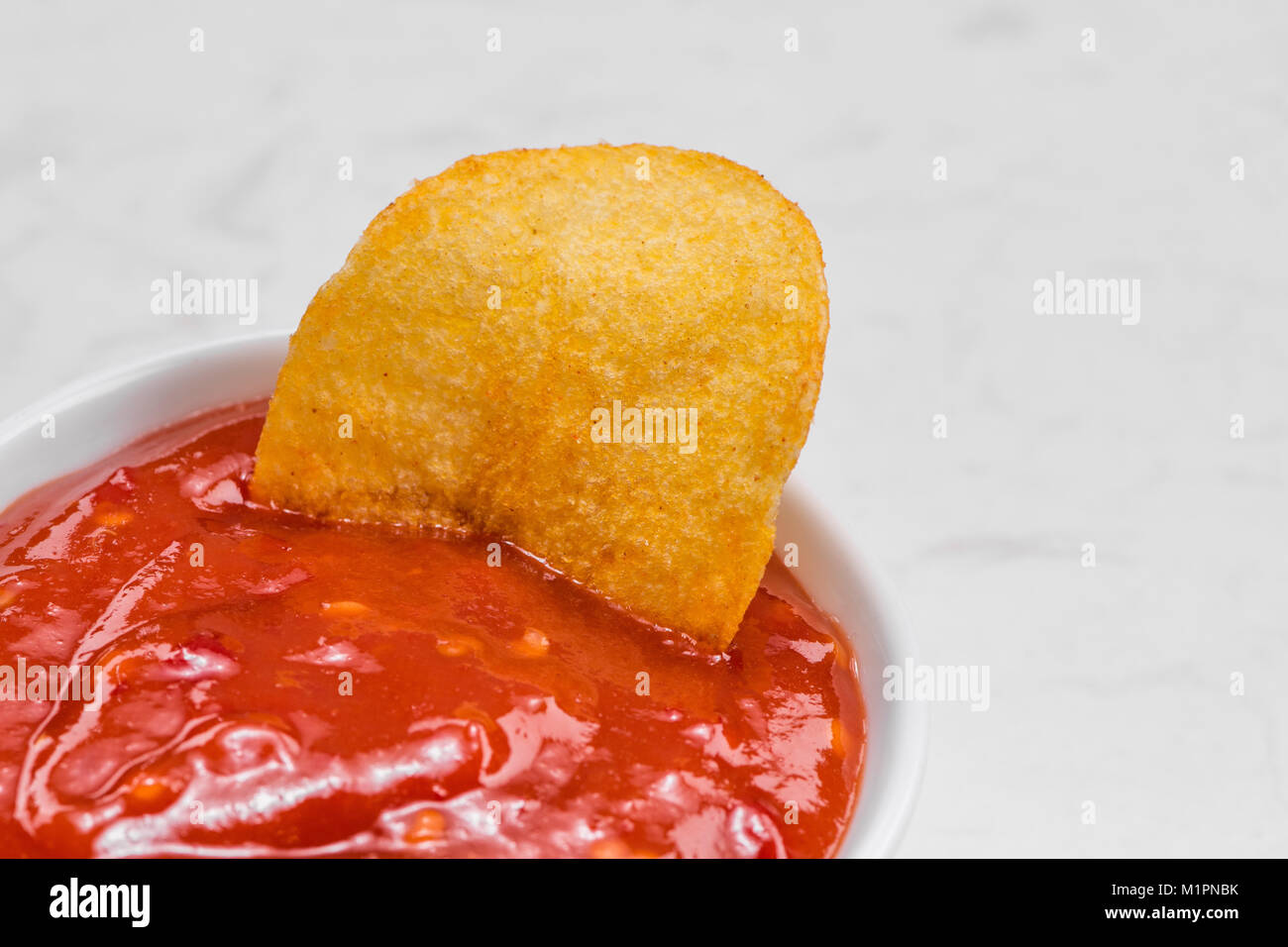 Konzept der ungesunde Nahrungsmittel. Zwiebel Kartoffelchips mit Hot Chili Sauce Stockfoto