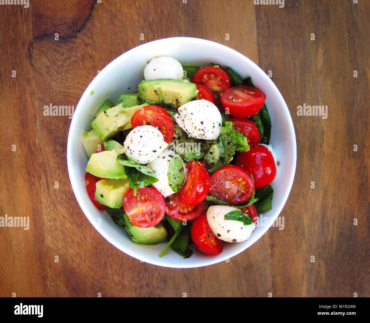 Frischer Salat oder Italienischer Salat in einer weißen Schüssel. Avocado, Cherry Tomaten und Mozzarella Salat mit frischem Basilikum. Nahaufnahme. Gourmet Salat. Stockfoto