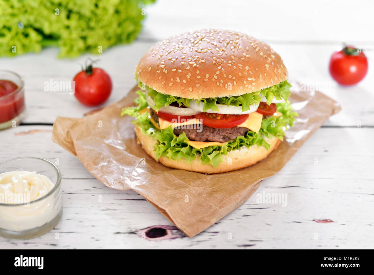 Gourmet Burger mit Soßen auf einem weißen Tisch. Hamburger oder Cheeseburger mit frischen Tomaten, Kopfsalat und Rindfleisch Patty, Fast food Hintergrund. Stockfoto