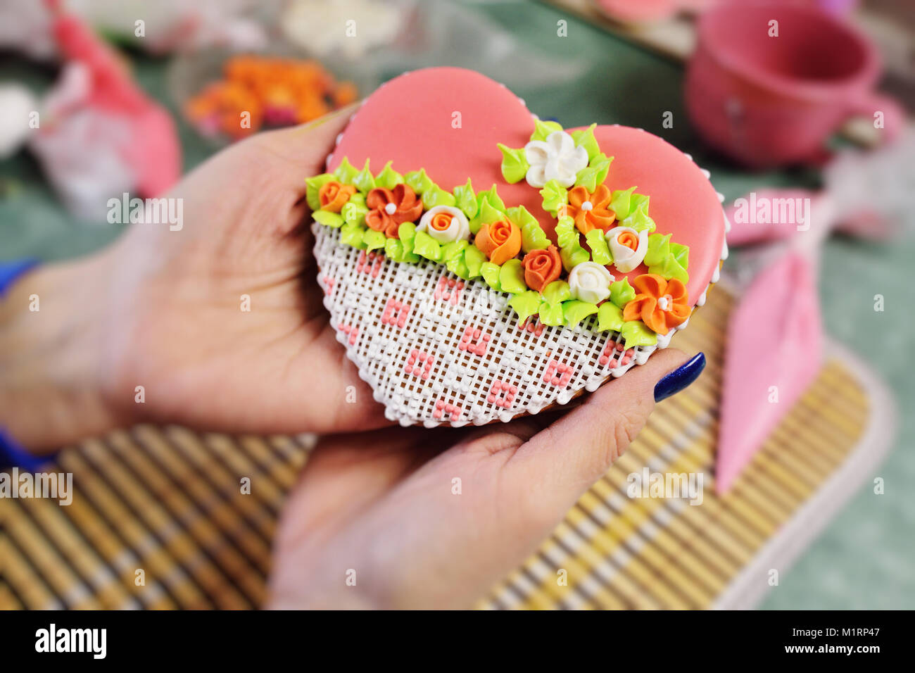 Frau Konditor schmückt und schmückt die Glasur mit Lebkuchen Kekse in der Form des Herzens. Stockfoto