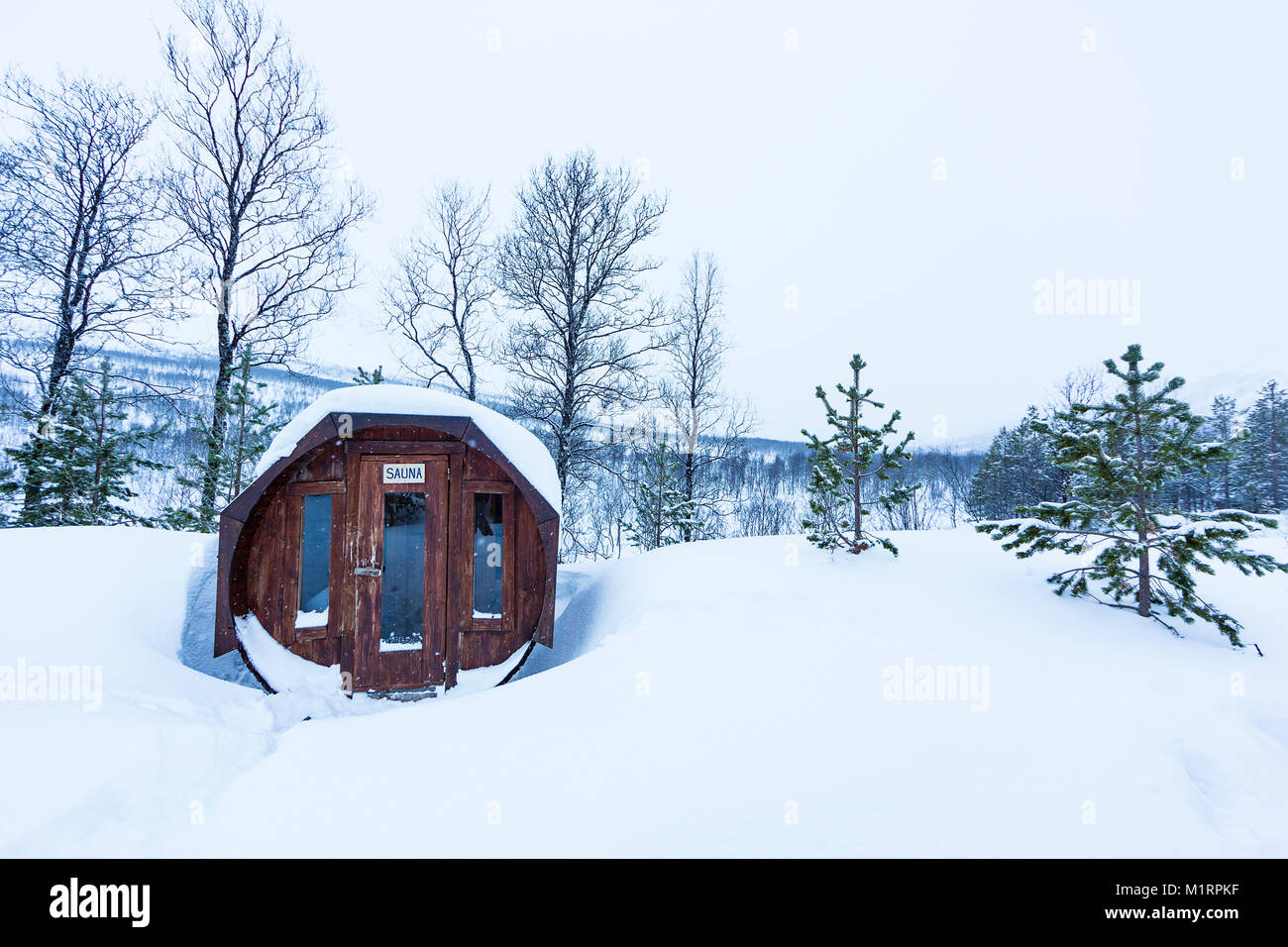 Skibotn, Norwegen. Holz- Sauna Gebäude gegen verschneite Hügel. Stockfoto