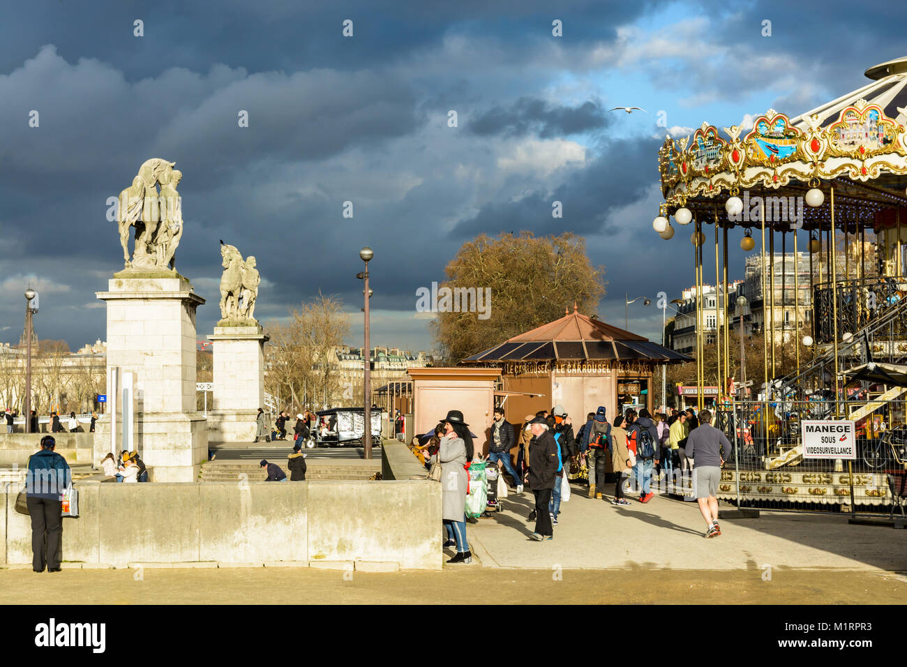 Menschen flanieren an den Ufern der Seine zwischen dem Karussell der Eiffelturm und die Statuen der Iena Brücke durch eine sonnige und stürmischer Tag. Stockfoto