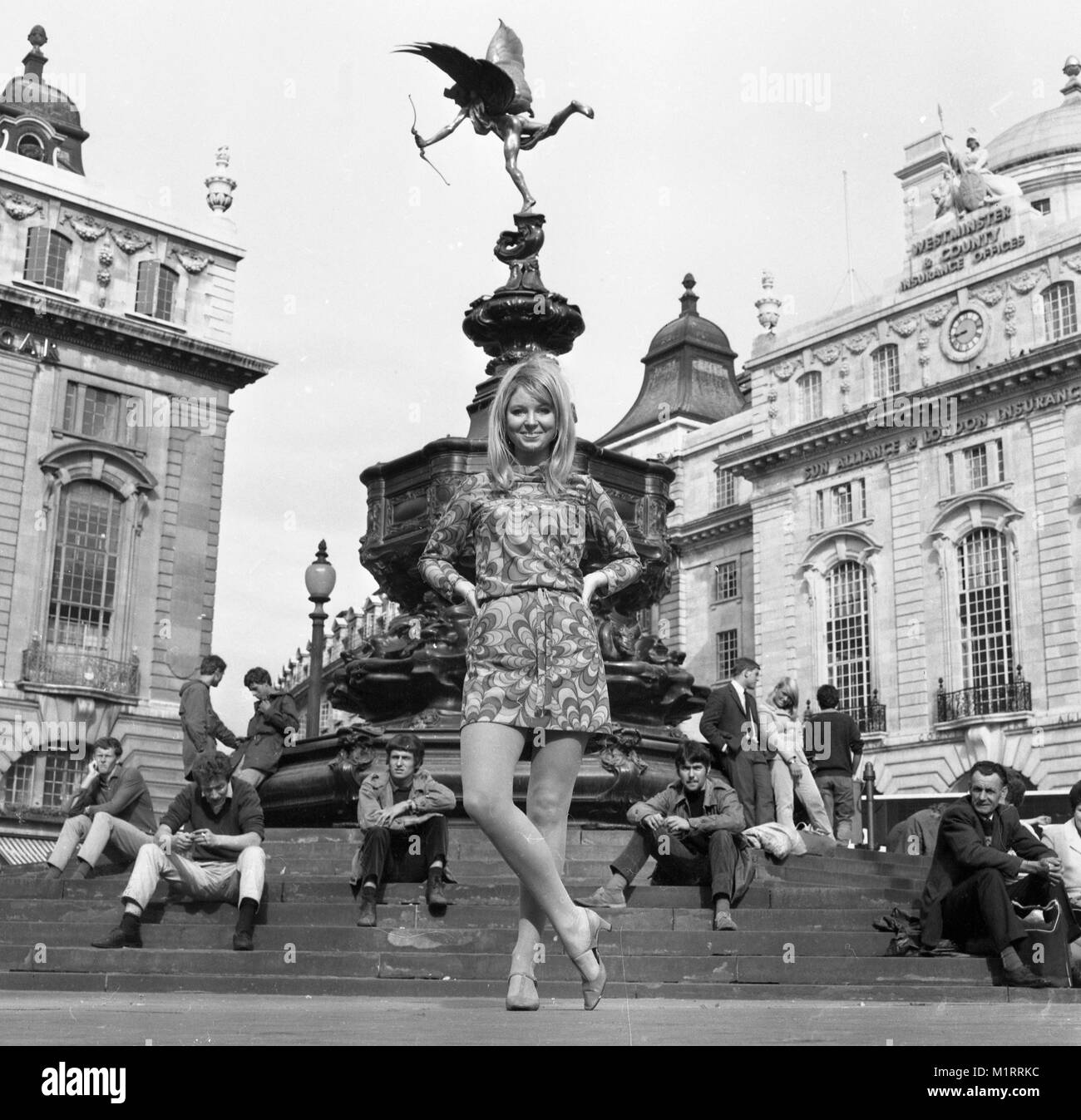 Ein Modell stellt in einem Mini Dress im Freien in Londons Piccadilly in der Nähe der Statue des Eros in ca. 1968 tragen eine bunte mini-kleid. Foto von Tony Henshaw Stockfoto