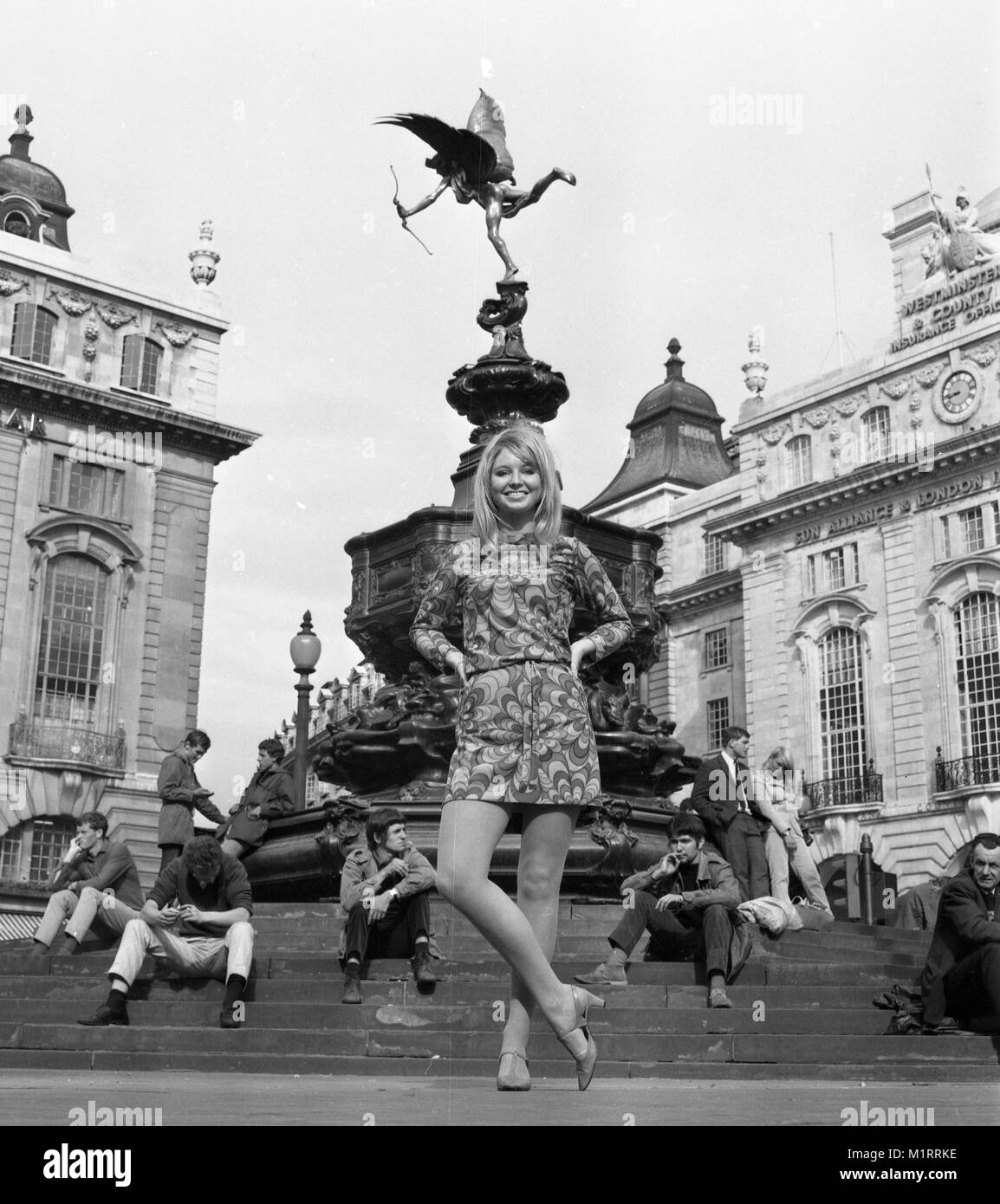 Ein Modell stellt in einem Mini Dress im Freien in Londons Piccadilly in der Nähe der Statue des Eros in ca. 1968 tragen eine bunte mini-kleid. Foto von Tony Henshaw Stockfoto