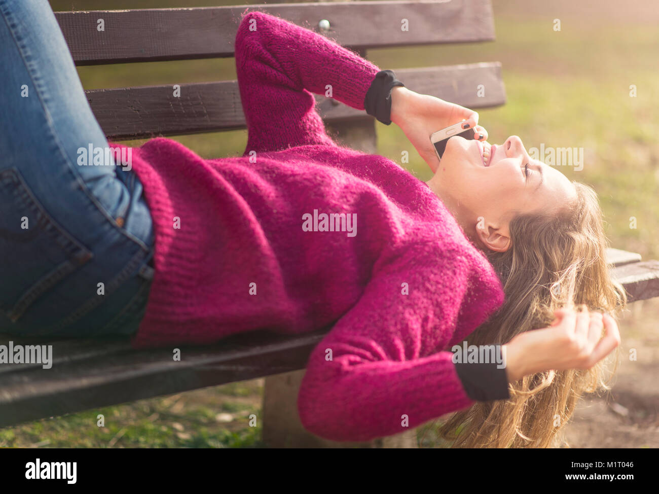 Kostenlose fröhliche Frau mit ihrem Handy in einem Park an einem sonnigen Tag Stockfoto