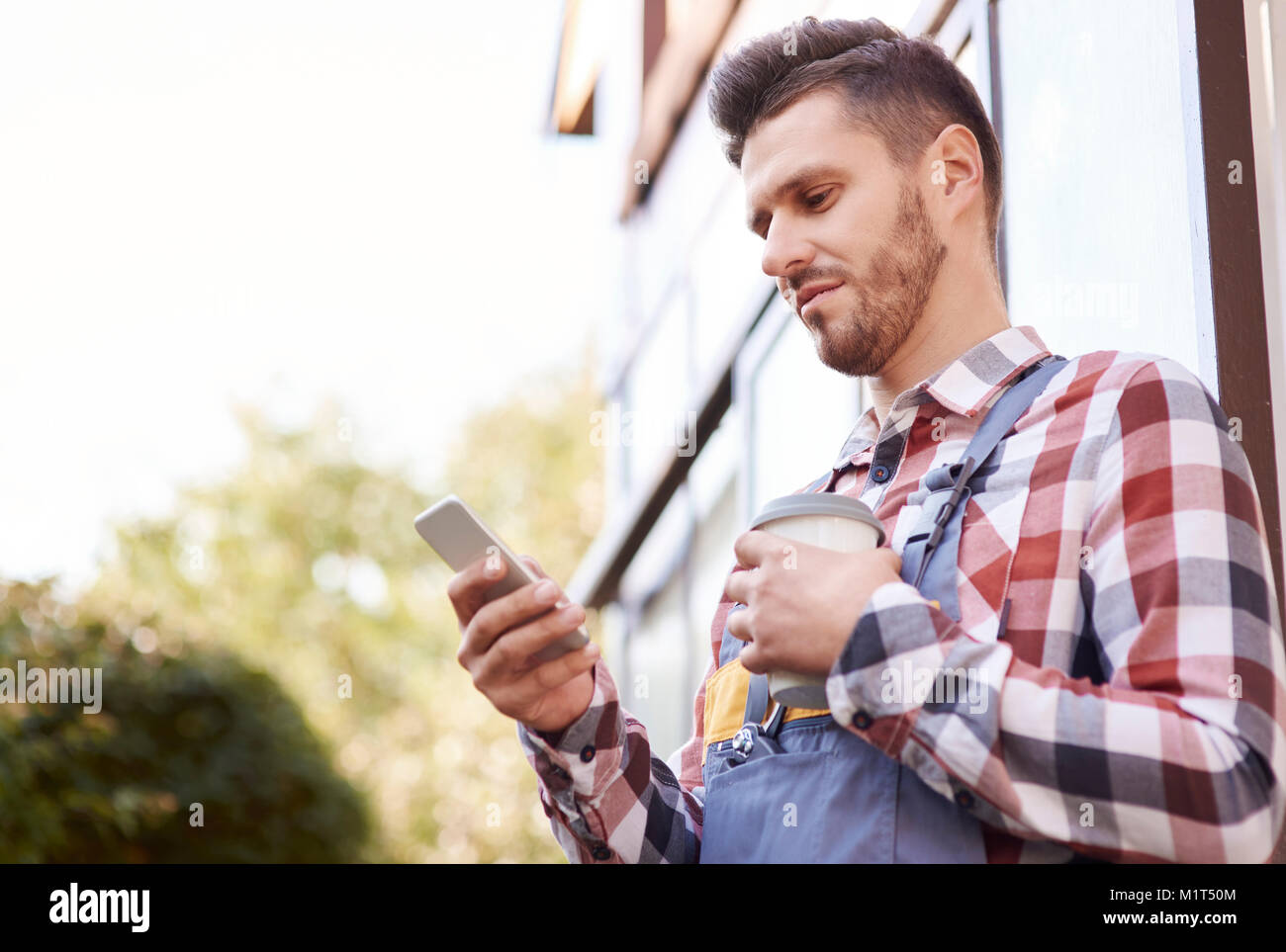 Gärtner mit über Handy Kaffee Stockfoto