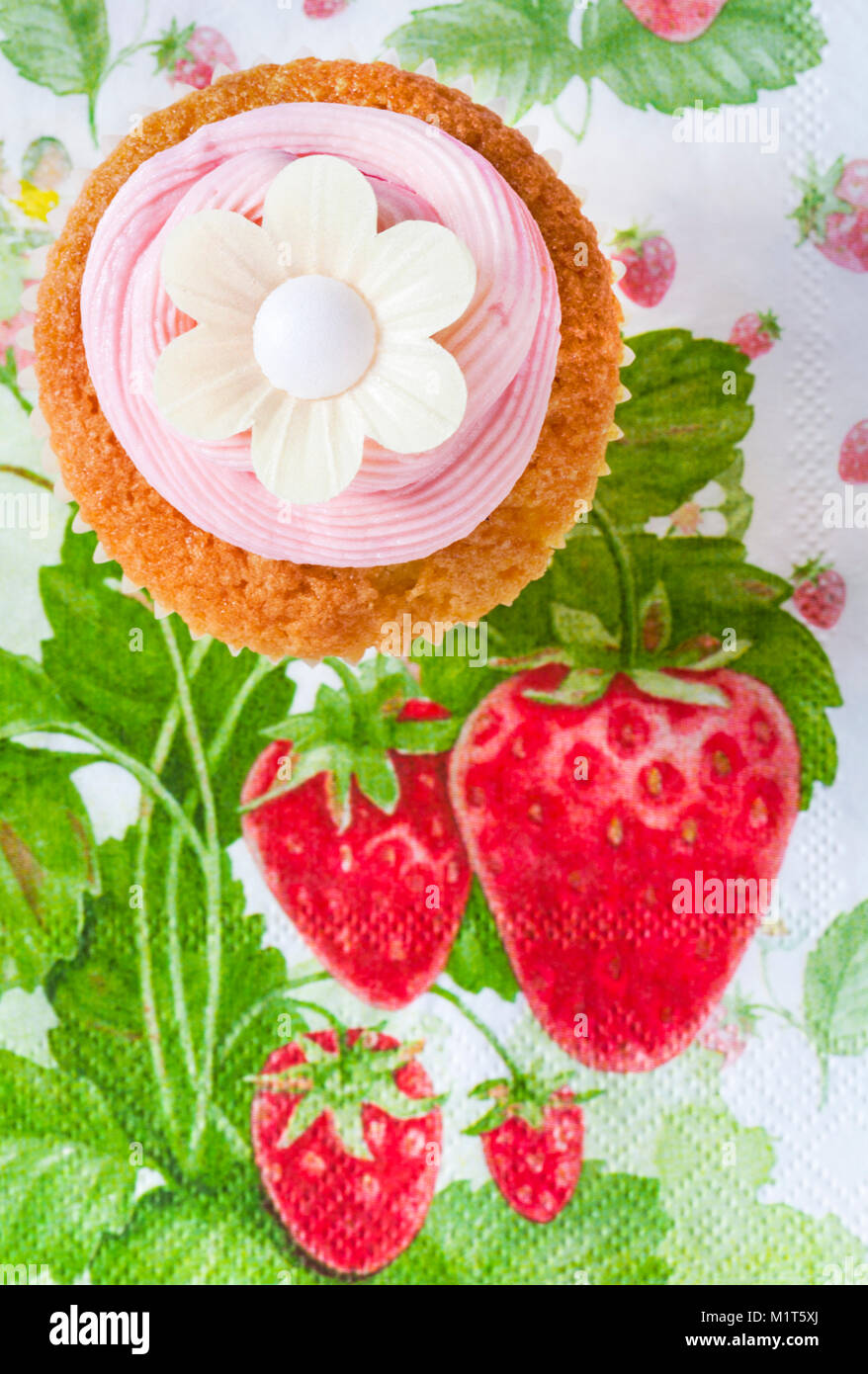 Hausgemachte Kuchen Kuchen mit Strawberry rosa Glasur Puderzucker und Reispapier genießbare daisy flower oben auf Erdbeere themed Serviette serviette Stockfoto