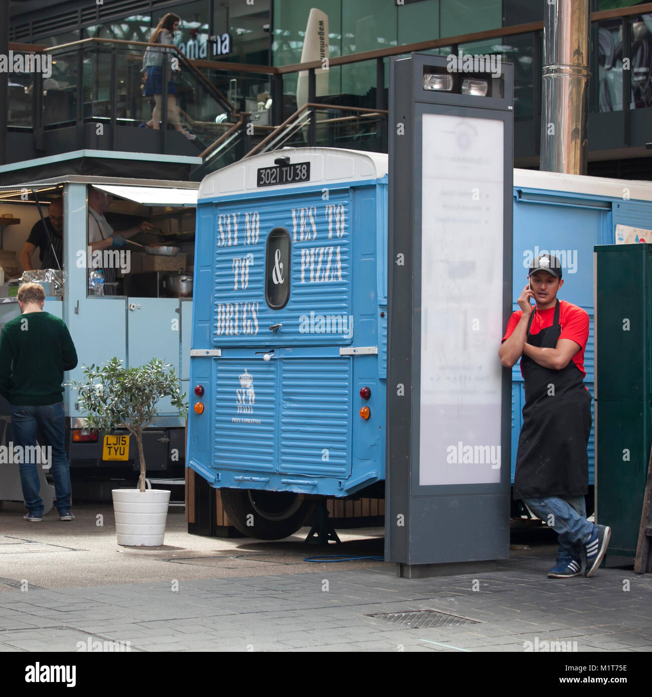LONDON, ENGLAND - 22. AUGUST 2017 eine Pizza Verkäufer in einem roten T-Shirt und Cap Gespräche am Telefon, stützte sich auf den Van in Spitalfields Market Stockfoto