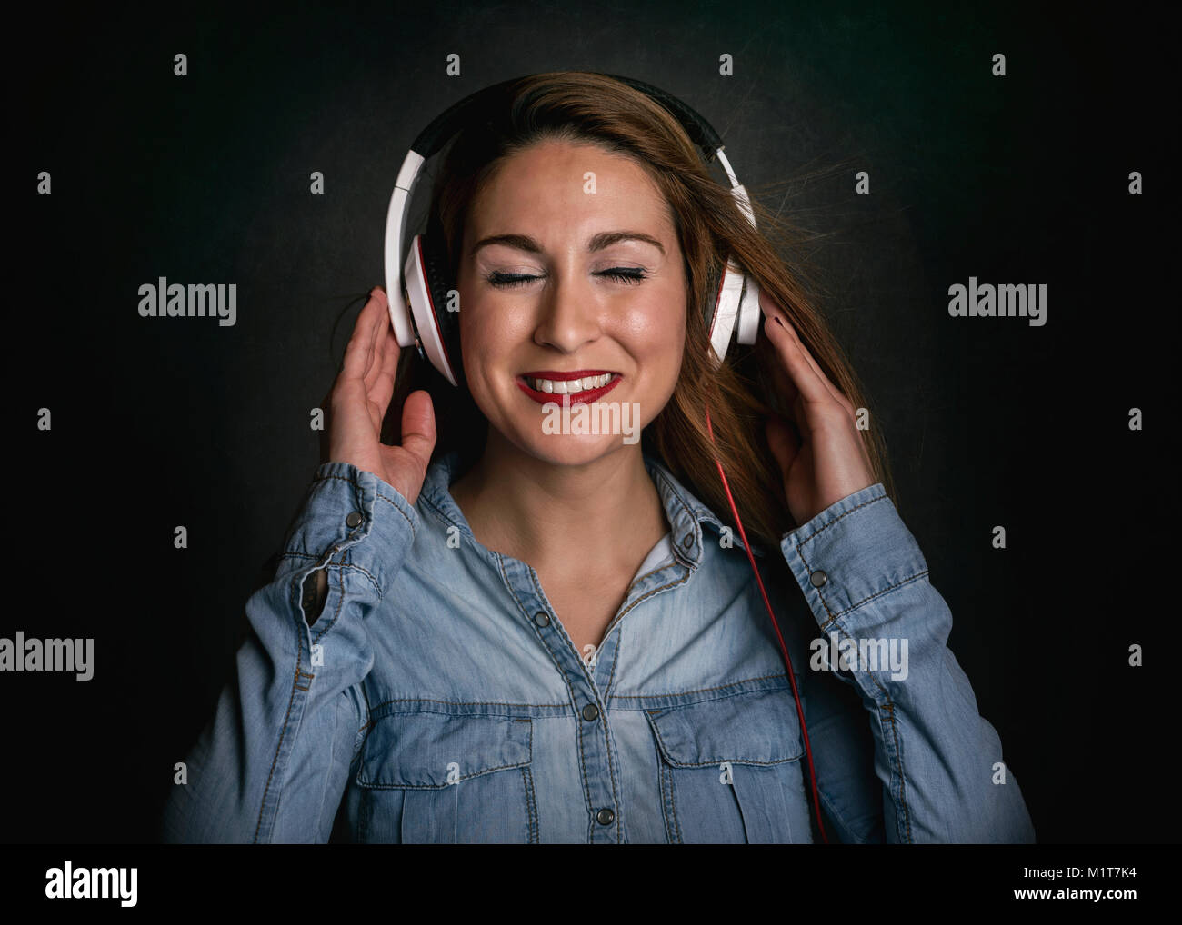 Glückliche junge Frau mit Kopfhörer auf schwarzem Hintergrund Stockfoto