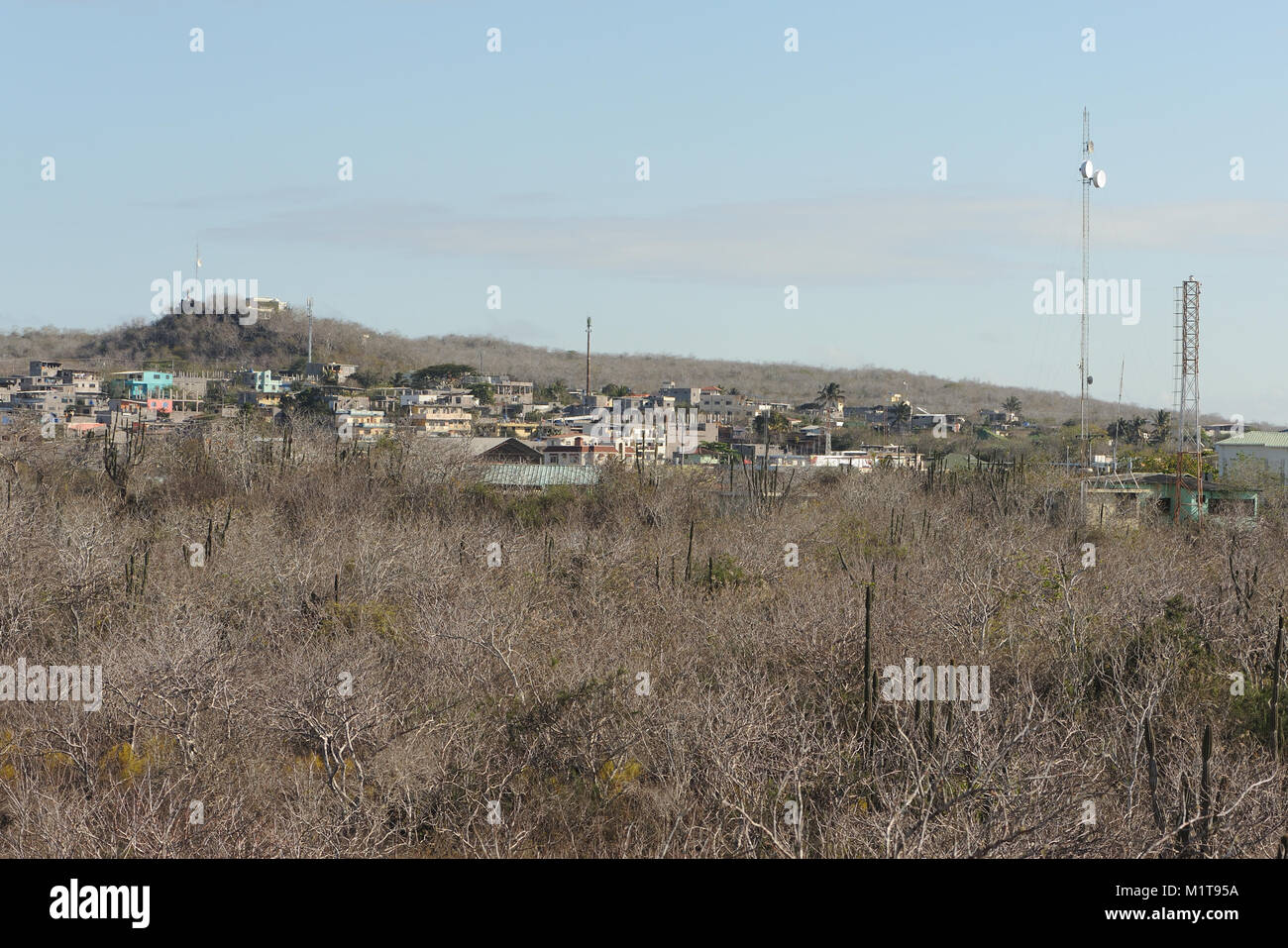 Gebäude und Kommunikation Masten unter den trockenen Gestrüpp der ariden Zone oberhalb von Puerto Baquerizo Moreno. Puerto Baquerizo Moreno, San Cristobal, Galapa Stockfoto