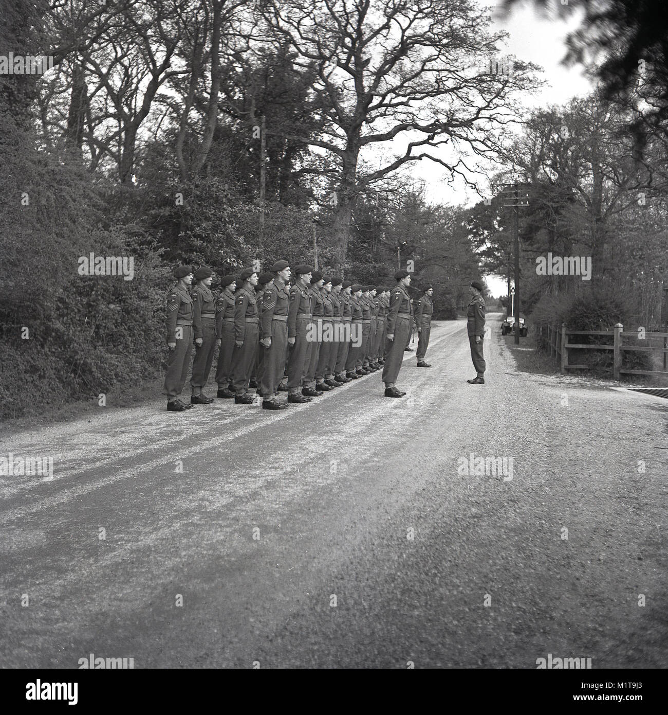 1955, historische, Bucks, England, Bild zeigt eine Truppe von britischen Soldaten auf einem Training Bohren im Freien, die Soldaten sind 'stehende an Aufmerksamkeit' in den Zeilen auf einer Schotterstraße in einem bewaldeten Gebiet. Stockfoto