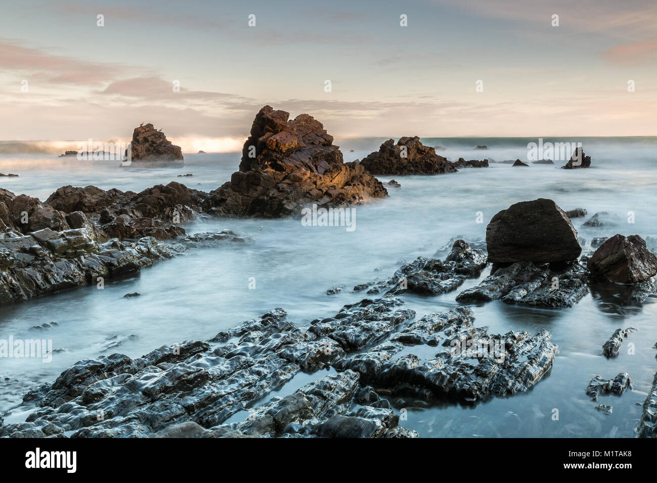 Dawn an den Stränden von Asturien, wo die Kraft des Meeres mit dem Felsen der Küste Zeichnen von Formen und Texturen spielt Stockfoto